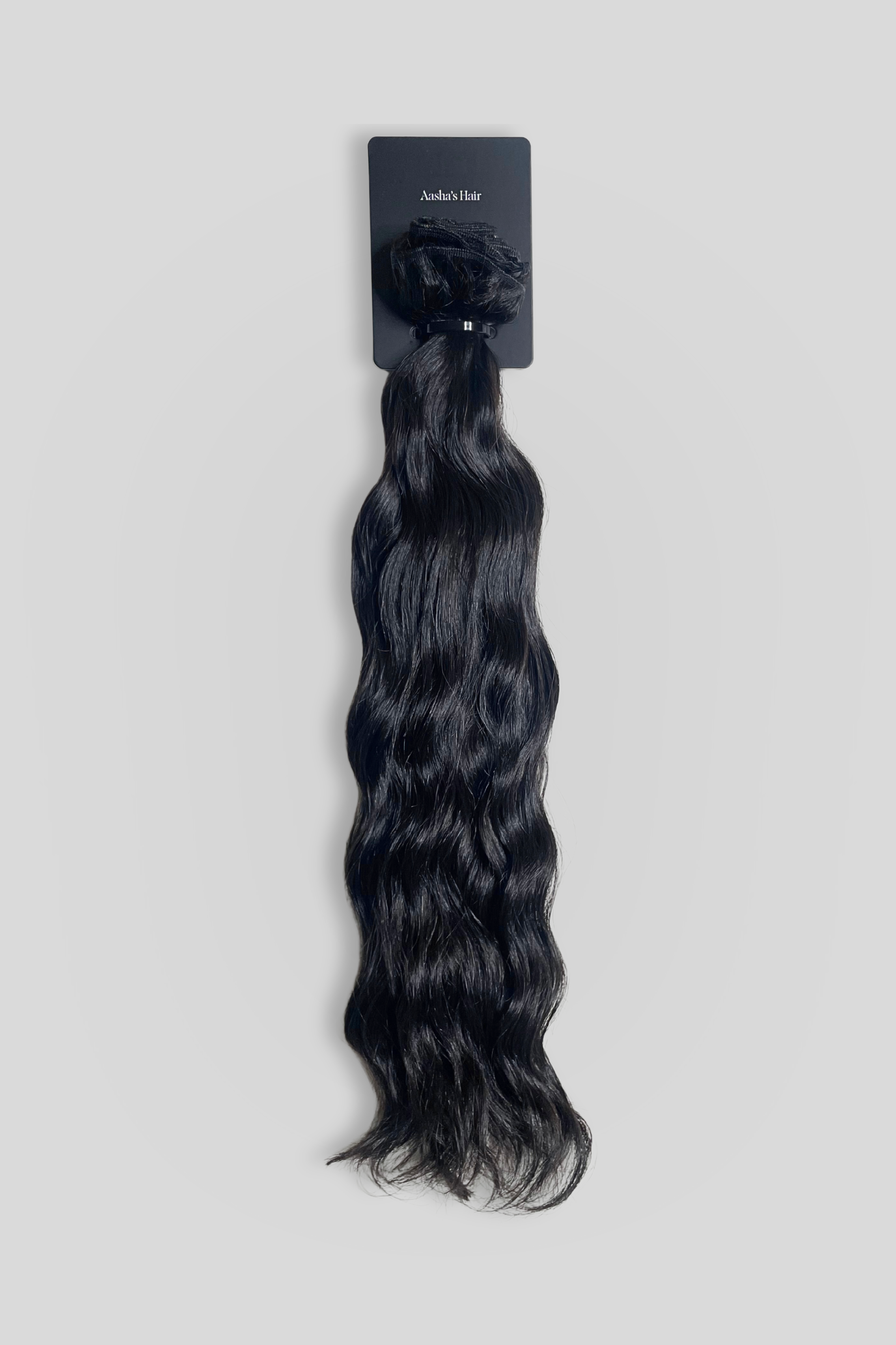 Black hair extensions on a gray background with a brand label.